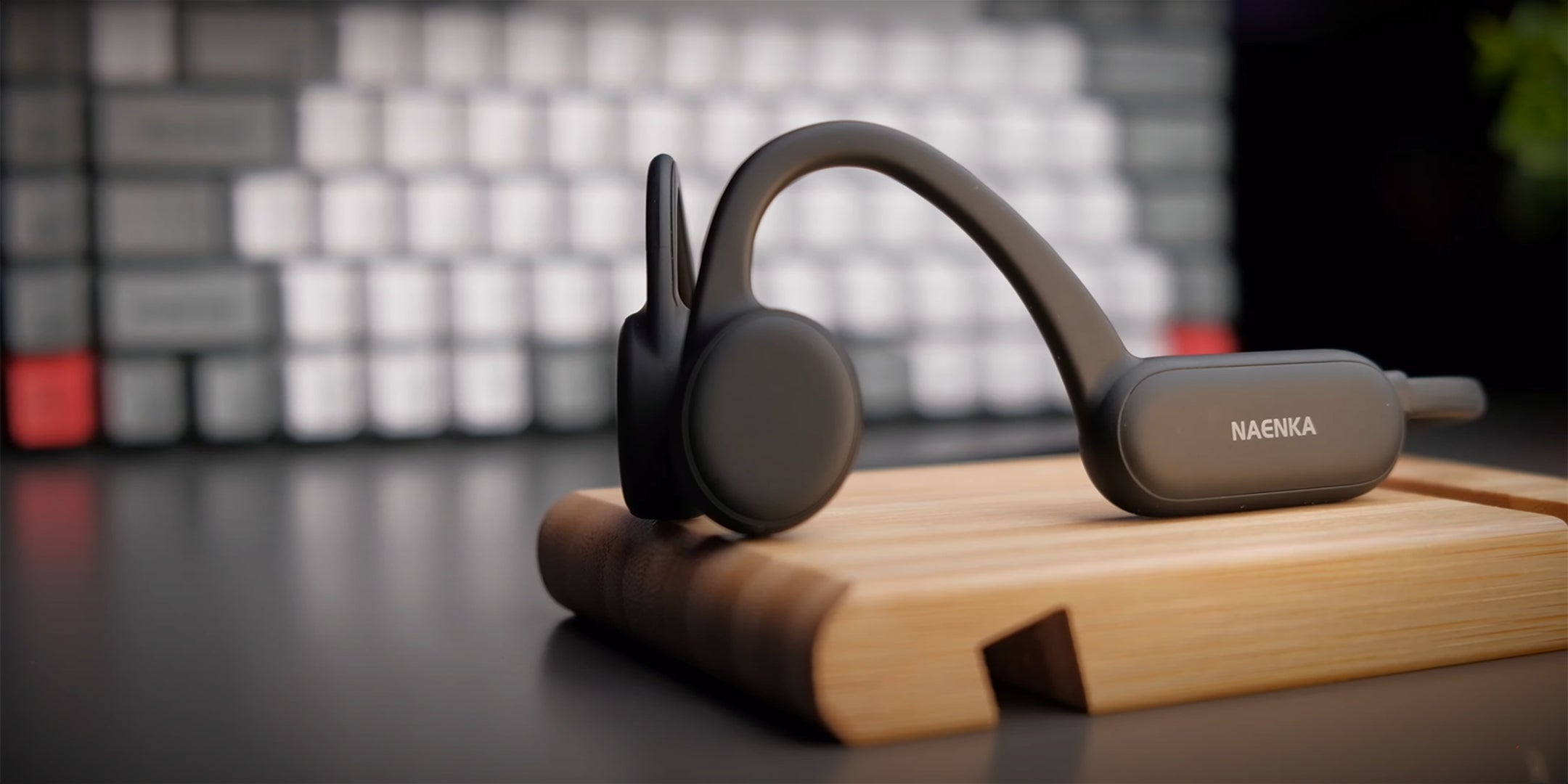 The black Naenka bone conduction headphones are placed on the tabletop
