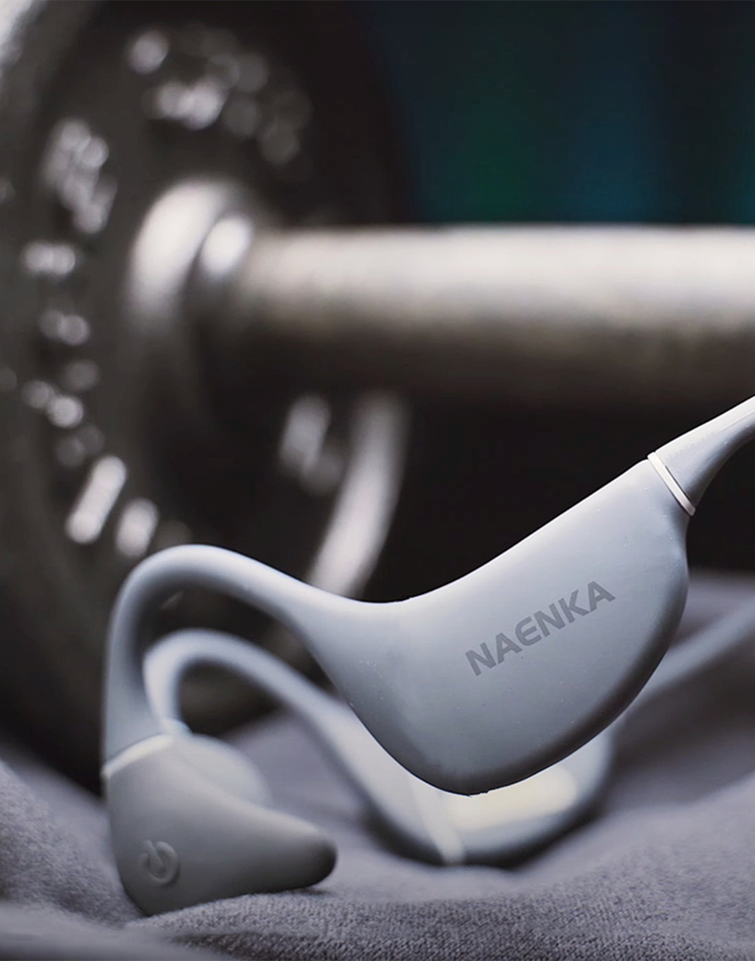 The gray Naenka bone conduction headphones are placed together with sports equipment